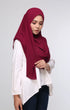 Woman wearing a Maroon Semi Instant Shawl Plain side view highlighting flowy edge and elegant drape and Navy blue pants on a light gray background