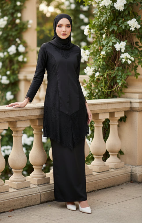 Woman in a Kebaya Moden Black outfit standing on a stone balcony with greenery and flowers in the background