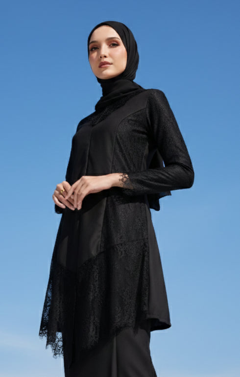 Woman wearing a Kebaya Moden Black close-up of French lace and soft cotton texture outfit with a Instant Shawl Black hijab against a blue sky
