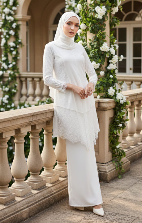 Woman in a Pearl White outfit Kebaya Moden side view on model highlighting long straight sleeves on a stone balcony with floral decorations.