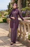 Woman wearing kebaya Kutu Baru Dusty Magenta front view showing V‑neck collar and French lace detailing standing outdoors with floral decorations.