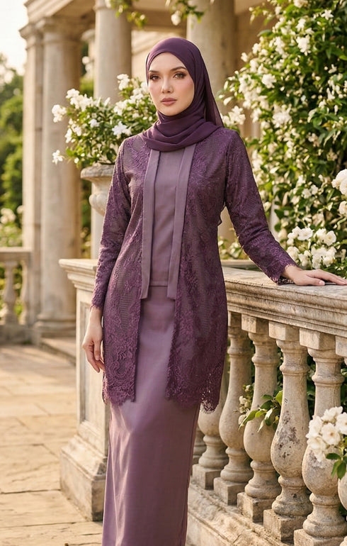 Woman wearing kebaya Kutu Baru Dusty Magenta front view showing V‑neck collar and French lace detailing standing on a stone balcony with floral decorations.