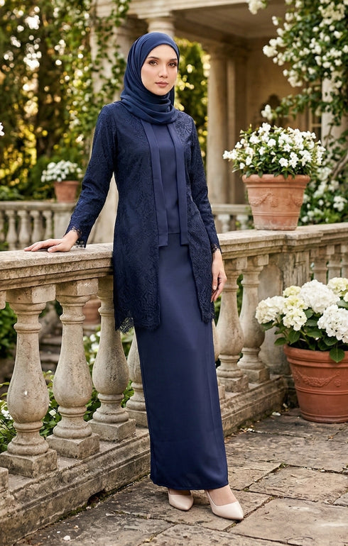 Woman in a baju kebaya Kutu Baru Navy Blue outfit standing outdoors with floral arrangements in the background