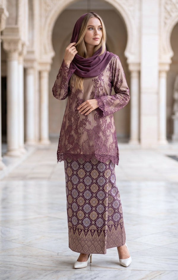 woman wearing Kurung Kedah Lace Songket Magenta full outfit with full songket skirt in an architectural setting.