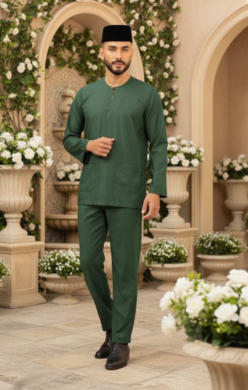 Man in Traditional Baju Melayu Teluk Belanga Emerald Green front view full outfit standing in a decorative outdoor setting with flowers and arches.