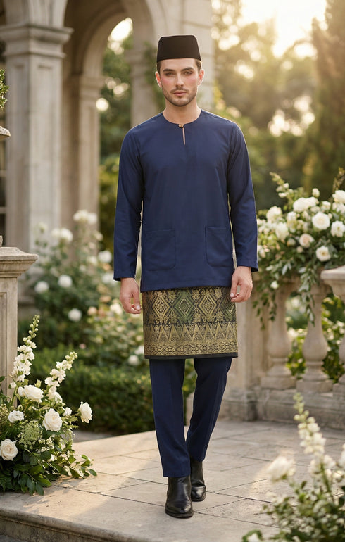 Man in traditional attire Baju Melayu Teluk Belanga Navy Blue standing in a decorative outdoor setting with flowers and architecture.