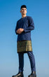 Man wearing a traditional Baju Melayu Teluk Belanga Navy Blue outfit and Sampin 3d Exclsuive against a clear blue sky.