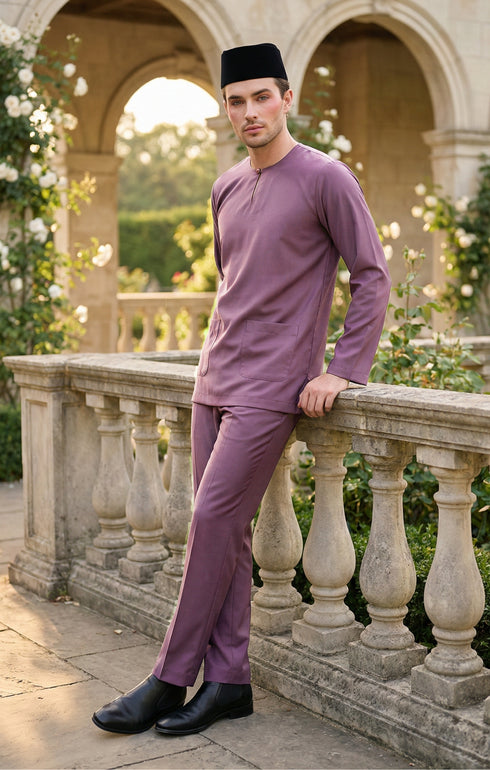 Man in a Smokey purple Baju melayu traditional outfit standing on a stone balcony with greenery in the background