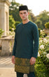 Man wearing a traditional Baju melayu Teluk Belanga outfit with a Teal green top and Tradiotional Sampin in an outdoor setting.