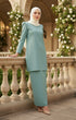Woman in a Kurung Moden Plain Dusty green full outfit view standing on a balcony with floral decorations.