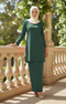 Woman in a Kurung moden plain dark emerlad green full outfit view standing on a balcony with floral decorations