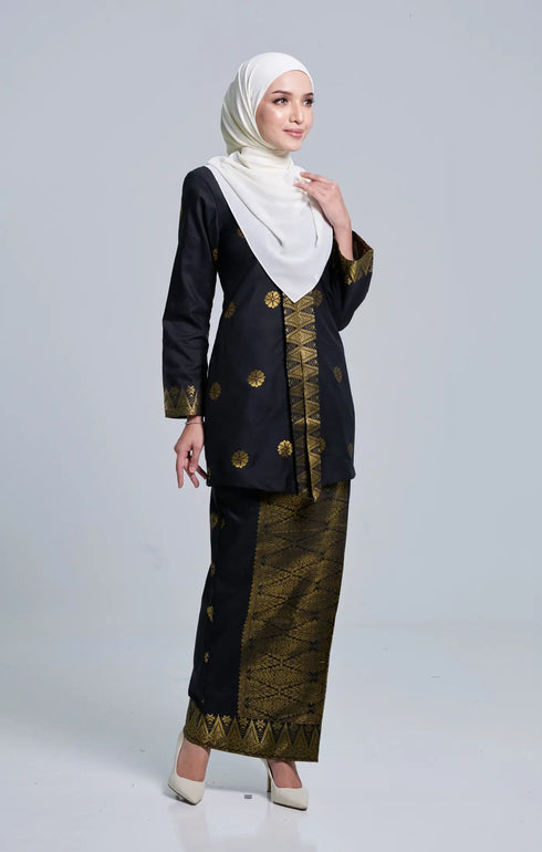 Woman wearing a traditional Seroja Kebaya Black Gold outfit with a hijab on a gray background