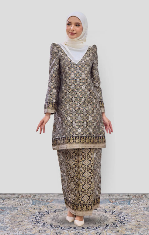 Woman wearing a Kurung Moden Black Gold Orchid showing brocade woven design and regular fit and instant shawl hijab on a white background