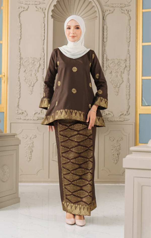 Woman wearing a Kurung Kedah Dark Rich Brown Gold traditional outfit with a matching Instant Shawl in an elegant interior setting.