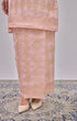 Model showing a Kurung Moden Baby Pink Gold traditional outfit with a brocade design on a patterned floor