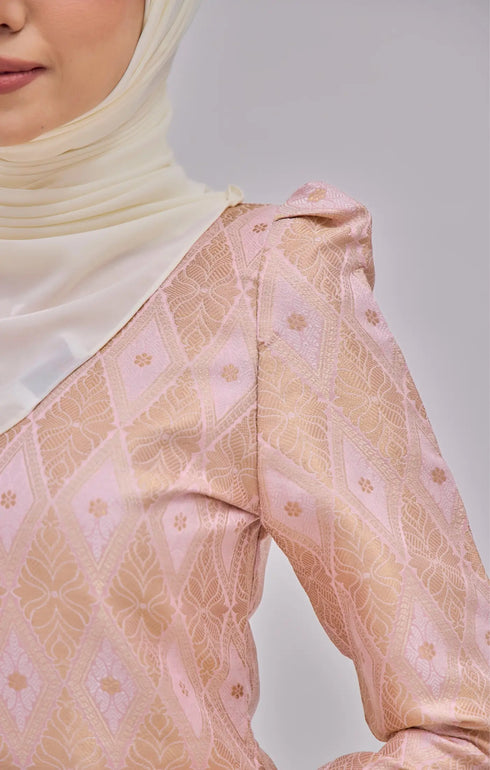 Close-up of a Kurung Moden Baby Pink Gold wearing pearl white instant shawl hijab against a gray background