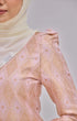 Close-up of a Kurung Moden Baby Pink Gold wearing pearl white instant shawl hijab against a gray background