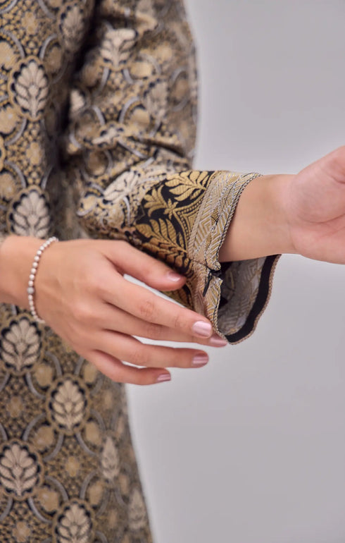 Close-up of Kurung Moden Black Gold Orchid showing dyed brocade texture and gold orchid accents