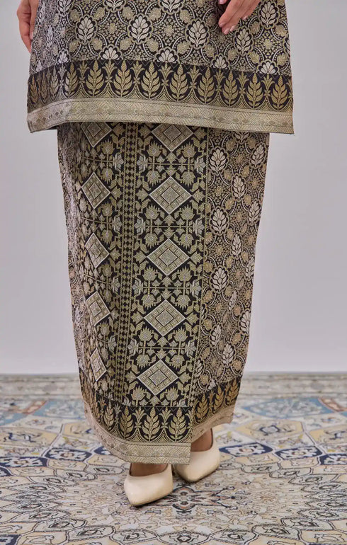 Traditional Kurung Moden Black Gold Orchid displaying outfit on a patterned floor