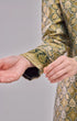 Fabric close up Kurung Moden Emerald Green Gold showing dyed brocade texture on plain background