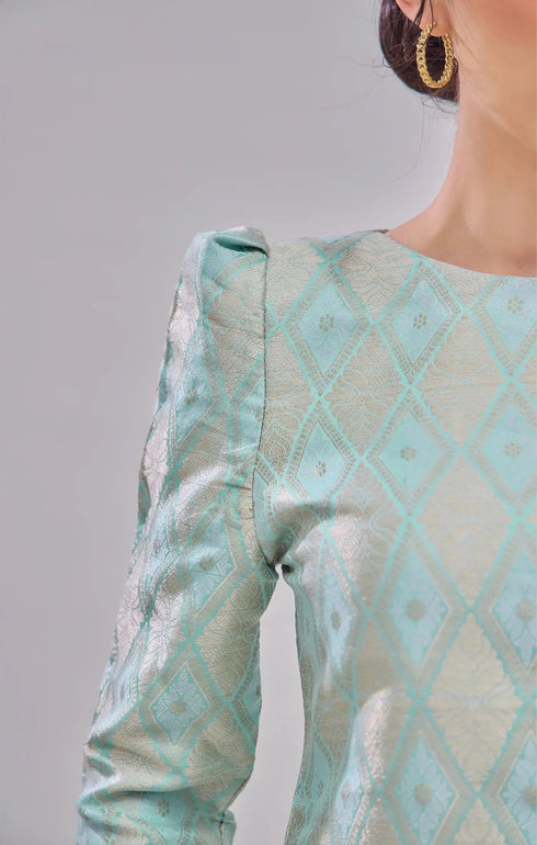 Kurung Moden Mint Green Gold highlighting fabric with a gray background