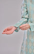 Model wearing a Kurung Moden Mint Green Gold highlighting long straight sleeve and silhouette outfit on a gray background