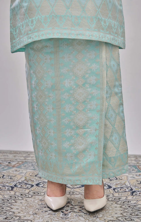 Kurung Moden Mint Green Gold showing dyed brocade texture skirt with white shoes on a patterned floor