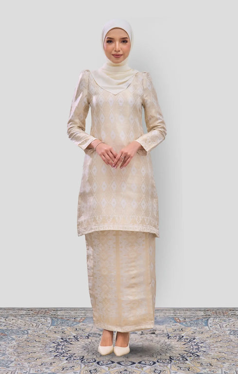 Woman wearing a Kurung Moden Off White Gold showing brocade woven design and regular fit with a pearl white matching hijab on a white background