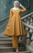 Woman in Kebarung Klasik Plain Mustard outfit standing on a staircase with decorative walls.