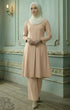 Woman in a Kebarung Klasik Nude cotton front view with V neck and labuh design standing in an elegant room with decorative walls.
