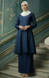 Woman in a Kebarung Klasik Plain Navy Blue full outfit view with lipat depan kain detail standing on a staircase with decorative walls.