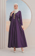 A model wearing a Jubah Kebarung Klasik Dark Purple, V-neck, long-sleeved, cotton plain traditional dress with a side pocket, standing in a circular mirrored background.