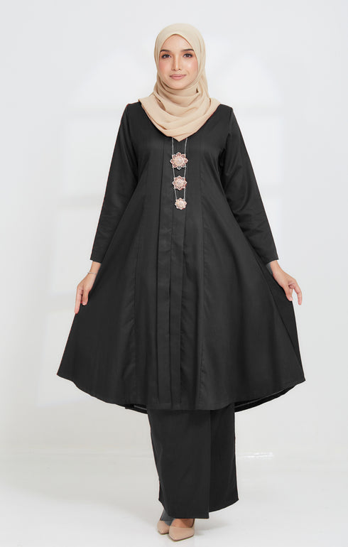 A woman wearing a traditional Kebarung Klasik Black outfit with a V-neck collar and long straight sleeves, paired with a front fold detail bottom
