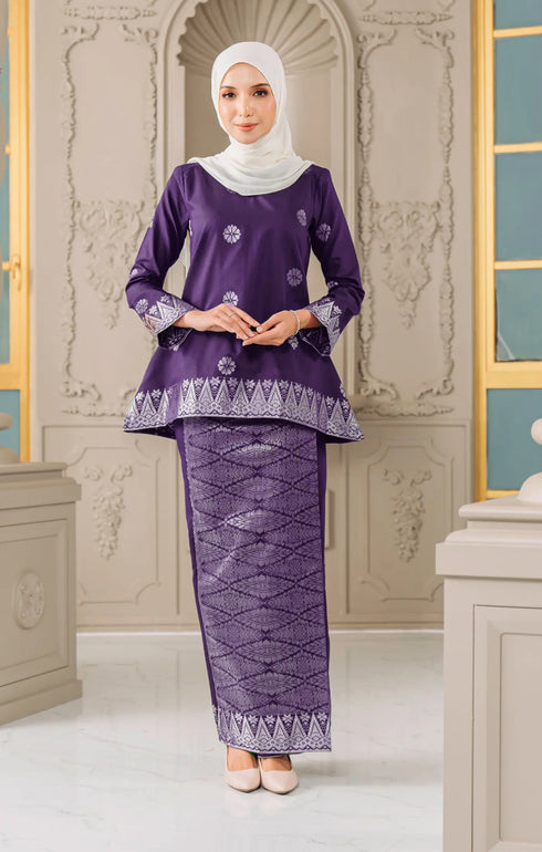 Woman wearing a Kurung Kedah Magenta Silver with a matching Instant hijab in an elegant interior setting.