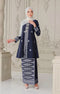 Woman wearing a Kebaya Blue Black Silver showing premium songket floral pattern traditional outfit with pearl white shawl in an ornate room.