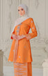 Woman wearing a Songket Kebaya Orange Silver showing in a decorative room.