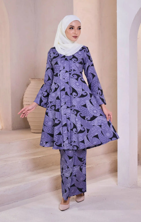 Woman wearing a Kebarung Pasley Dusty Blue outfit with a shawl white hijab in an elegant interior setting.