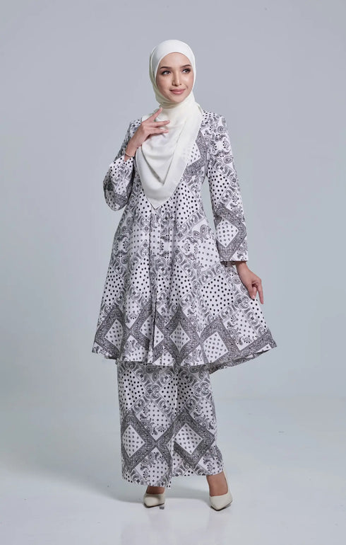 Woman wearing a Kebarung Black White highlighting long straight sleeve and silhouette with a instant shawl hijab on a gray background