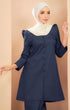 A woman wearing a Kurung Riau Plain Navy Blue traditional dress with a V-neckline, long sleeves, and a back zip.