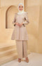A woman wearing a Kurung Riau Plain nude colored with a V-neck top and long straight sleeves, paired with matching trousers. She is standing in a room with a neutral background.