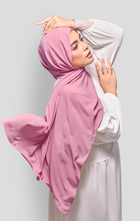 Woman wearing a Dusty Pink Royal Satin Shawl Plain Hijab side view highlighting flowy edge and generous width white outfit against a gray background