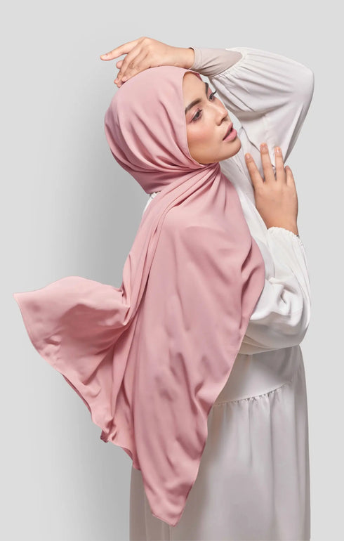 Woman wearing a Rose Gold Royal Satin Shawl Plain Hijab side view highlighting flowy edge and generous width white outfit against a gray background