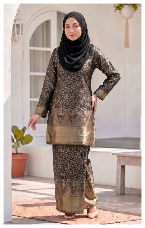 Model wearing a Kurung Moden Black full outfit with lipat depan kain and lining traditional outfit standing outdoors.