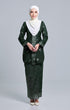 A woman wearing an Kebaya Dark Emerald Green Silver songket pattern, consisting of a long-sleeved top with a V-neck collar and a matching skirt, paired with a pearl white instanl shawl scarf
